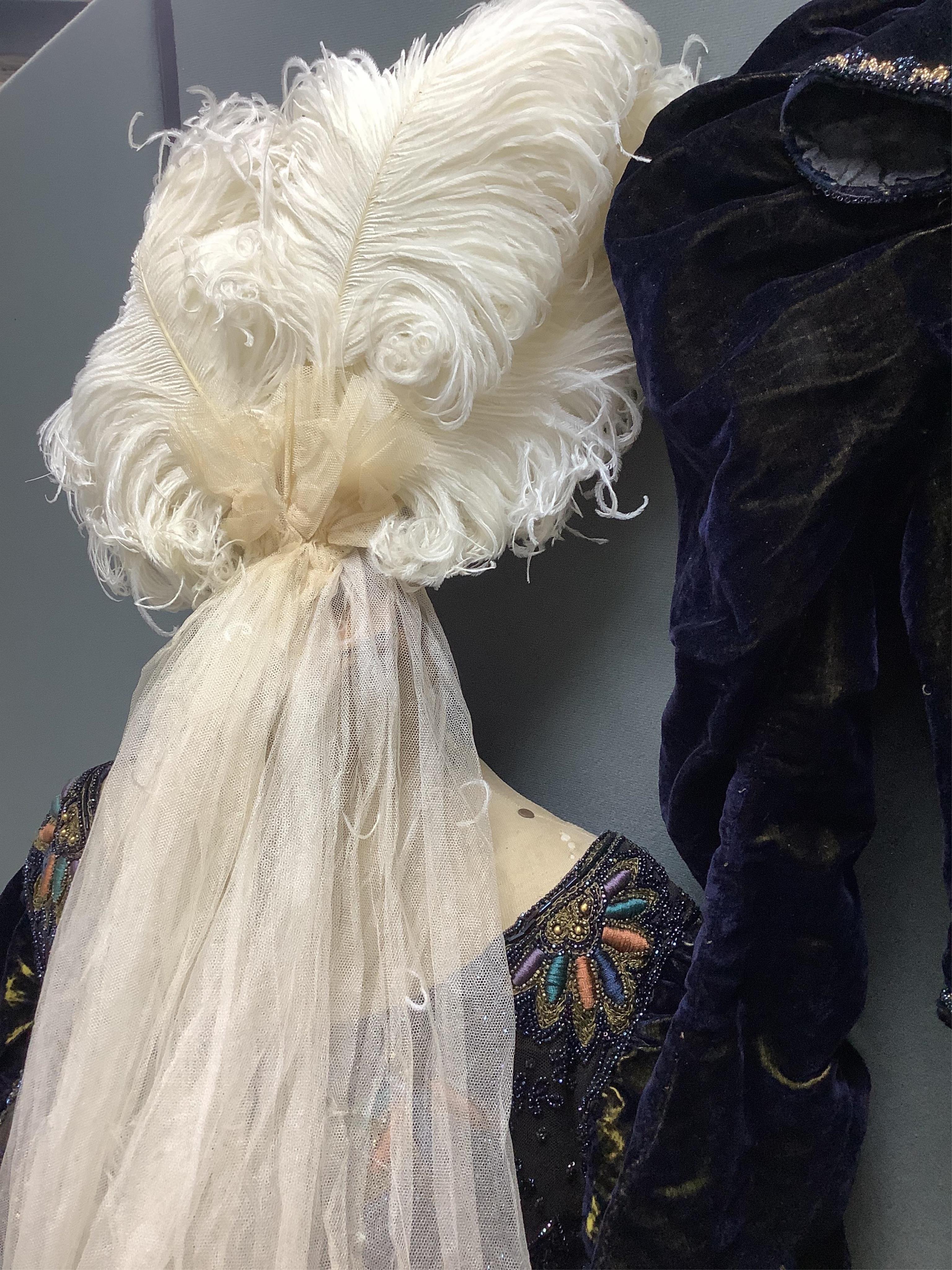 A 19th century ladies silk velvet matching long sleeved jacket/bodice, and skirt, together with another matching short sleeved bead worked bodice and white feather headdress.(4). Cape 106cm long. Condition - Both bodices